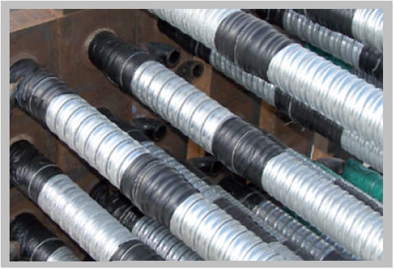 Corrugated galvanised steel post-tensioning ducts laid side by side in a steel form, each with a black heat shrink coupler recovered over the connection between two duct lengths